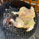 A whole chicken on a hot charcoal grill
